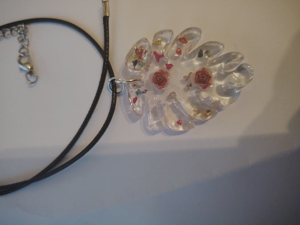 Pendant necklace made of cast UV resin in the shape of a leaf. Filled with two roses and colorful glitter stones.